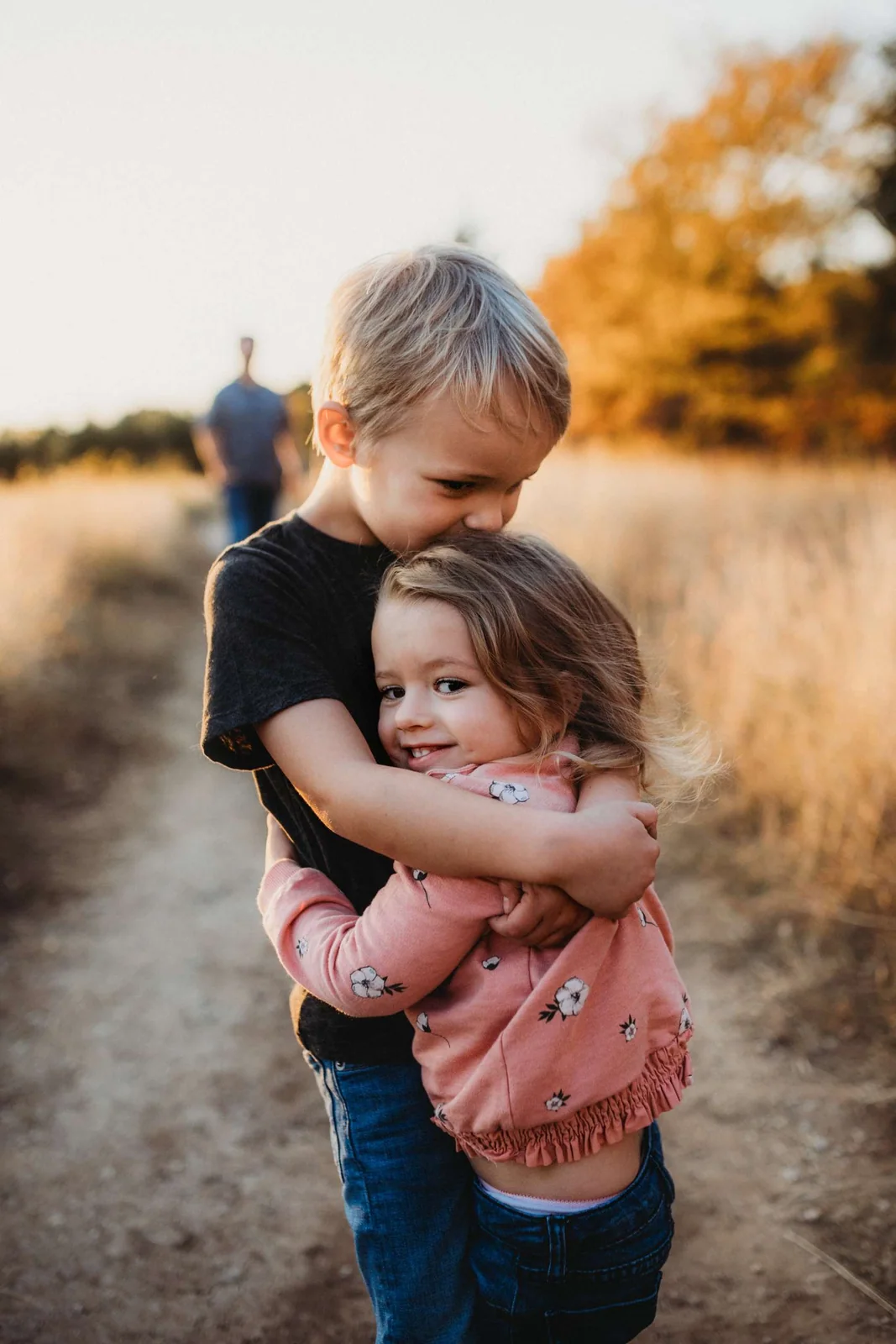 Two young children hugging in a field